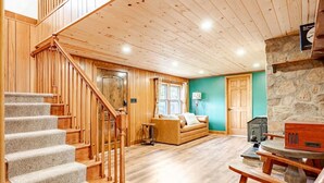 A wooden staircase leading to a living area with a sofa and a stone wall.