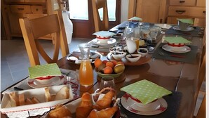 Een eettafel met eten, drinken en een laptop.