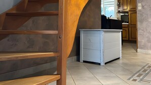 Een houten trap met een bordje waarop 'MAISON BONHEUR' staat, die leidt naar een keuken met kastjes en een aanrecht.