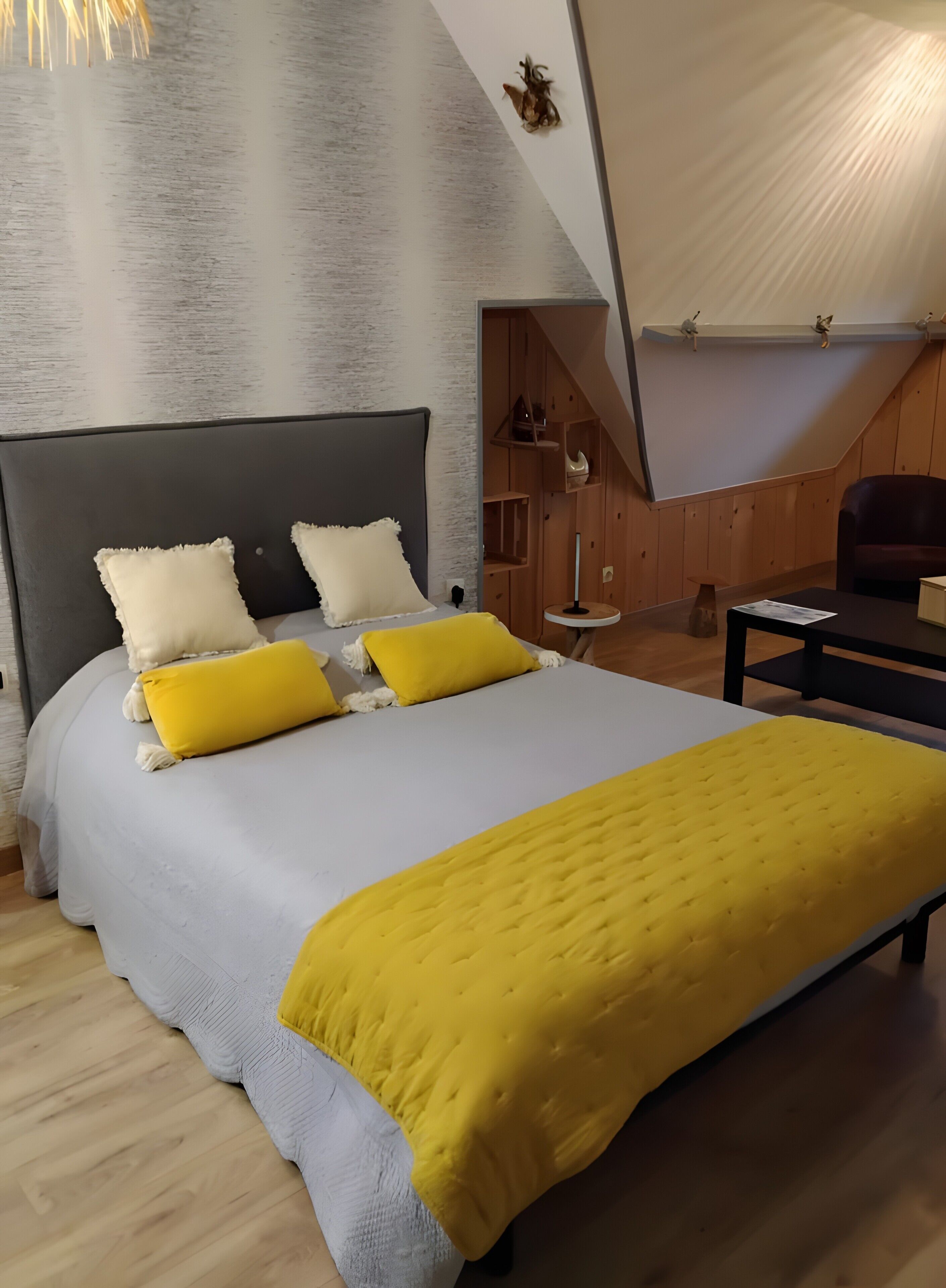 Ein modernes Schlafzimmer mit einem großen Bett, einem hölzernen Kopfteil und einem außergewöhnlichen, schrägen Deckenbau.