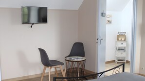 A bedroom with a bed, a TV mounted on the wall, two chairs, a small round table, and a white nightstand with decorative items. - Bed and Breakfast 'Nature' with Shared Terrace, Shared Garden and Wi-Fi (Videcosville)