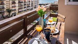 A balcony with a table set for breakfast, a vase of tulips, and a view of the sea and buildings. - LAGOON VISTA BY ALFRESCO STAYS (Benalmádena)