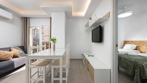A modern, well-lit room with a dining table, chairs, a sofa, a bed, and a TV. - LAGOON VISTA BY ALFRESCO STAYS (Benalmádena)