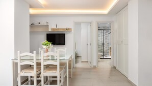 A modern kitchen with white cabinetry, a glass dining table, and a flat-screen TV mounted above it. - LAGOON VISTA BY ALFRESCO STAYS (Benalmádena)