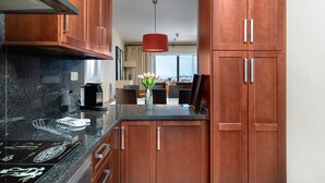 A modern kitchen with wooden cabinets, a granite countertop, and a red pendant light.