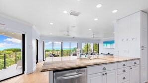A modern kitchen with white cabinets, a granite countertop, and a dishwasher. - Breathtaking Beach Views - 3bed on Siesta! (Siesta Key)