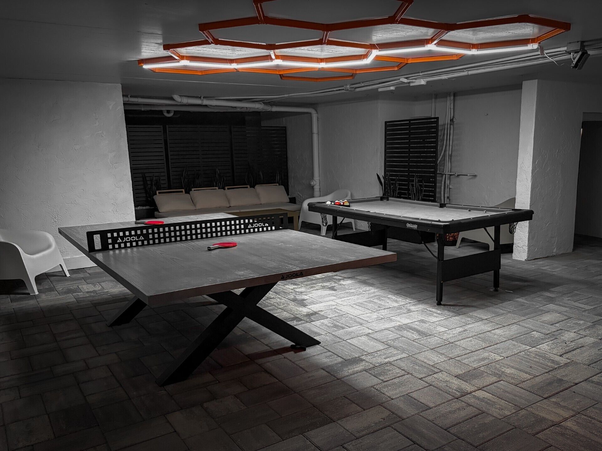 A billiards table with a net in a room with a tiled floor and a ceiling light fixture.