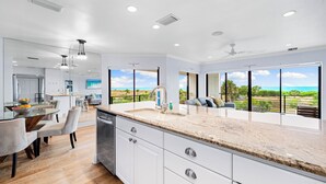 A modern kitchen with a large island, white cabinetry, and a view of the outdoors. - Breathtaking Beach Views - 3bed on Siesta! (Siesta Key)