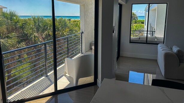 A modern interior with a balcony overlooking a beach and ocean. - 3bed on Siesta w/ direct beach access! (Siesta Key)