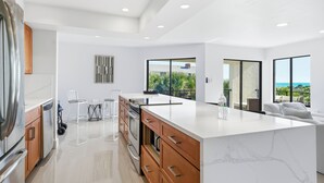 A modern kitchen with a large island, wooden cabinets, and a view of greenery outside. - 3bed on Siesta w/ direct beach access! (Siesta Key)