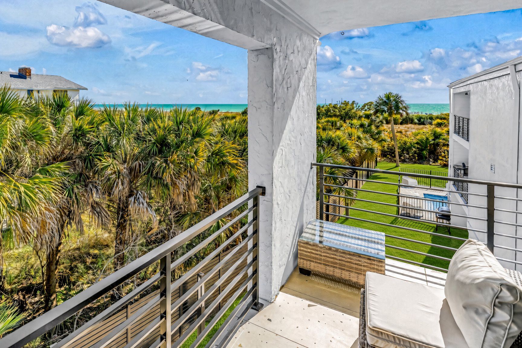 A balcony with a view of the ocean and a pool area.