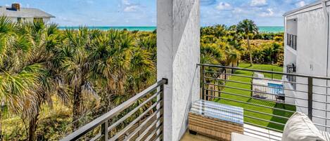 A balcony with a view of the ocean and a pool area.
