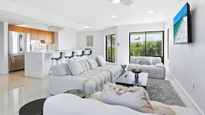 A modern living room with a sectional sofa, a coffee table, and a TV mounted on the wall. - 3bed on Siesta w/ direct beach access! (Siesta Key)