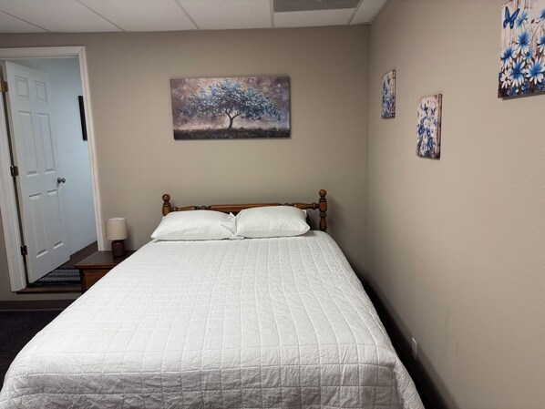 A bedroom with a bed, a door, and wall art.