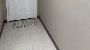 A hallway with a white door, a framed picture of geese, and a thermostat on the wall.