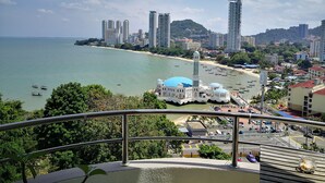 Un paysage urbain côtier avec une mosquée imposante, de hauts immeubles et une plage.