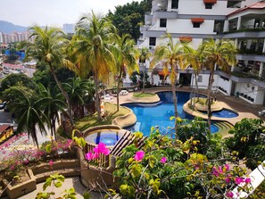 Ein Resort mit mehreren Schwimmbecken, Palmen und Blick auf eine Stadtlandschaft.