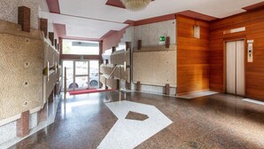 A modern lobby with a polished stone floor, a staircase, and a wooden wall. - Large two-room apartment City Life - Mirable PM (Milano)