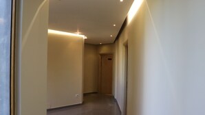 A corridor with a light-colored floor and walls, leading to a door at the end. - Danis Hotel (Golem)
