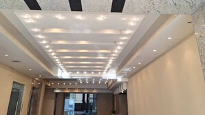 A modern hotel lobby with a high ceiling, recessed lighting, and a geometric marble design. - Danis Hotel (Golem)