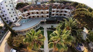 A multi-story hotel with a central courtyard, palm trees, and a swimming pool. - Danis Hotel (Golem)