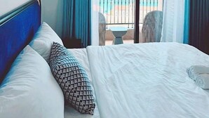 Una habitación de hotel con una cama grande, vistas al mar y un balcón con sillas.