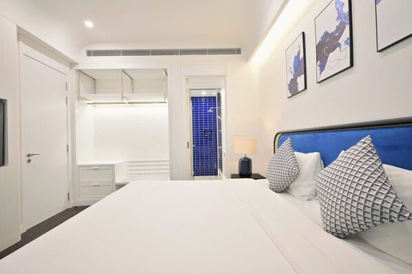 A modern hotel room with a large bed, a walk-in closet, a bathroom with blue tiles, and artwork on the wall. - Hillside risedence Phu Quoc (Phu Quoc)