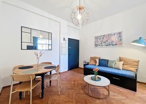 A modern living room with a dining area, a sofa, a coffee table, and a hanging light fixture.