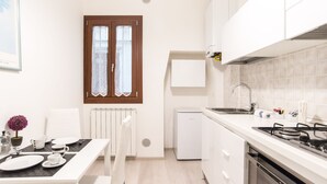 Une cuisine compacte avec des meubles blancs, un four encastré et un évier.
