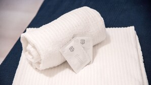 Une serviette blanche, soigneusement pliée, avec une étiquette, posée sur une surface bleue texturée.