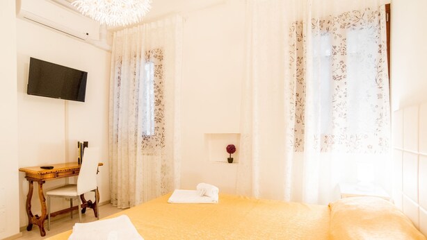 Une chambre d’hôtel avec un lit, un bureau, une chaise, une télévision et une fenêtre avec des rideaux.
