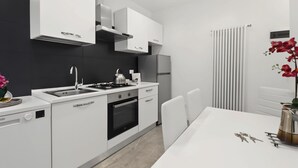 A modern kitchen with white cabinetry, a gas stove, a built-in oven, and a dishwasher.