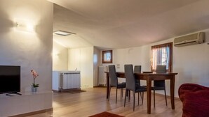 A modern living room with a flat-screen TV, a dining table with chairs, a red armchair, and a radiator. - Magic View - WiFi (Venezia)