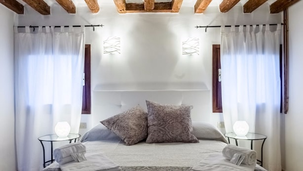 A bedroom with a large bed, two nightstands, and a ceiling with exposed wooden beams. - Magic View - WiFi (Venezia)
