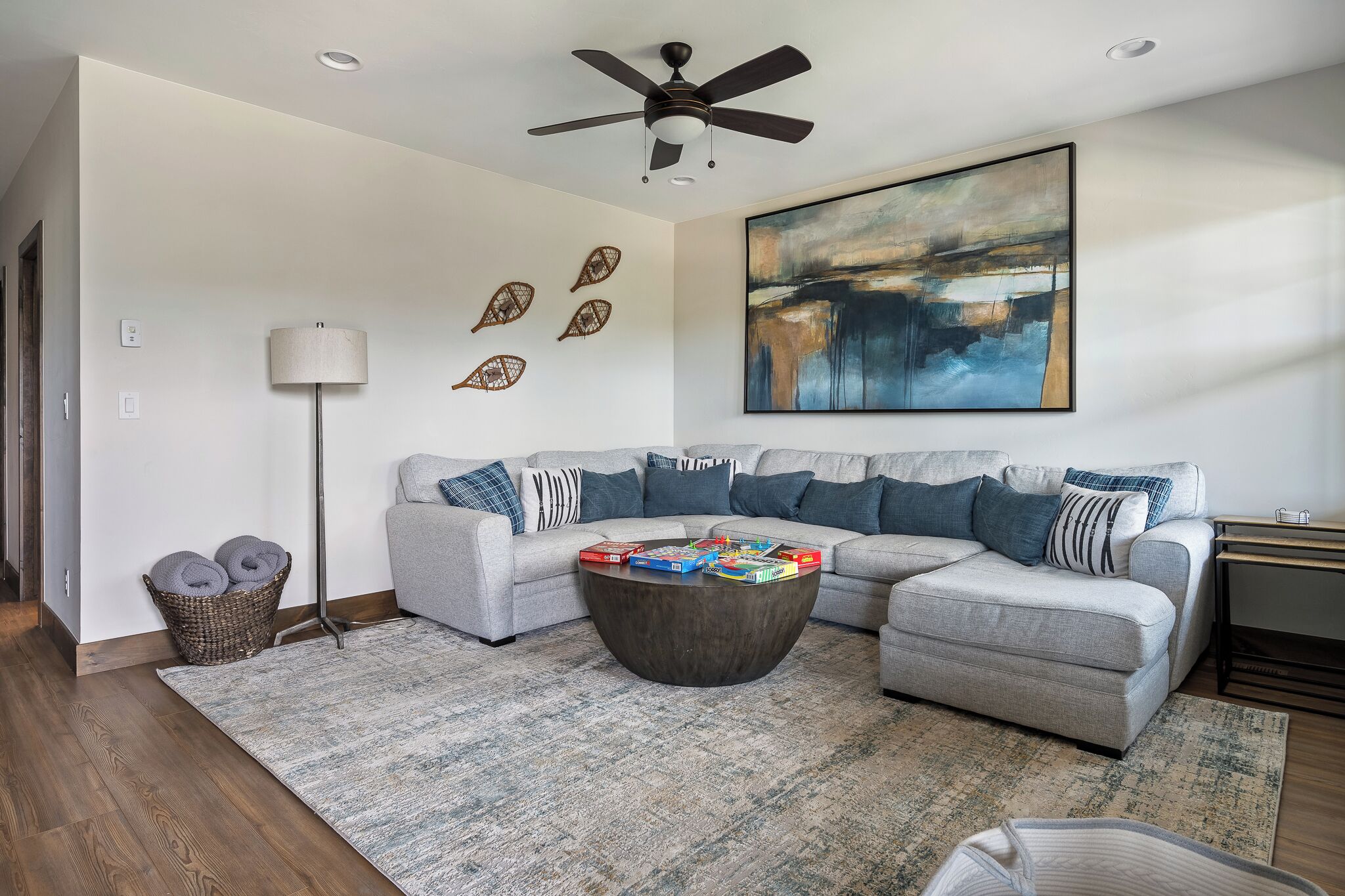 A modern living room with a grey sectional sofa, a round coffee table, and a ceiling fan.