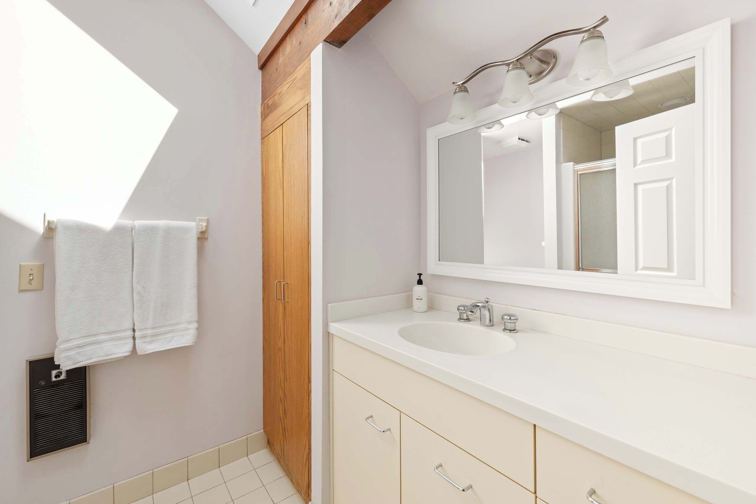 Une salle de bain moderne avec un grand miroir, un lavabo et un meuble en bois.