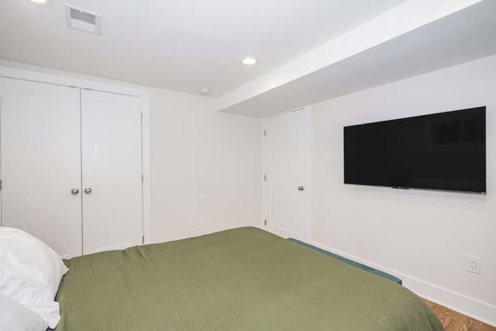Un dormitorio con cama, televisión montada en la pared y armario.