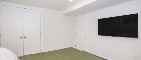 Un dormitorio con cama, televisión montada en la pared y armario.
