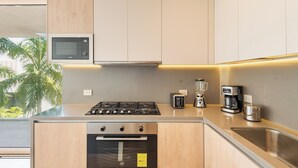 A modern kitchen with a built-in microwave, stove, oven, and a coffee maker. - Alba Puerto Cancun (Cancun)