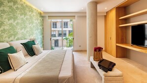 A modern hotel room with a bed, a sofa, a TV, and a large window offering a view of the building's exterior. - Alba Puerto Cancun (Cancun)