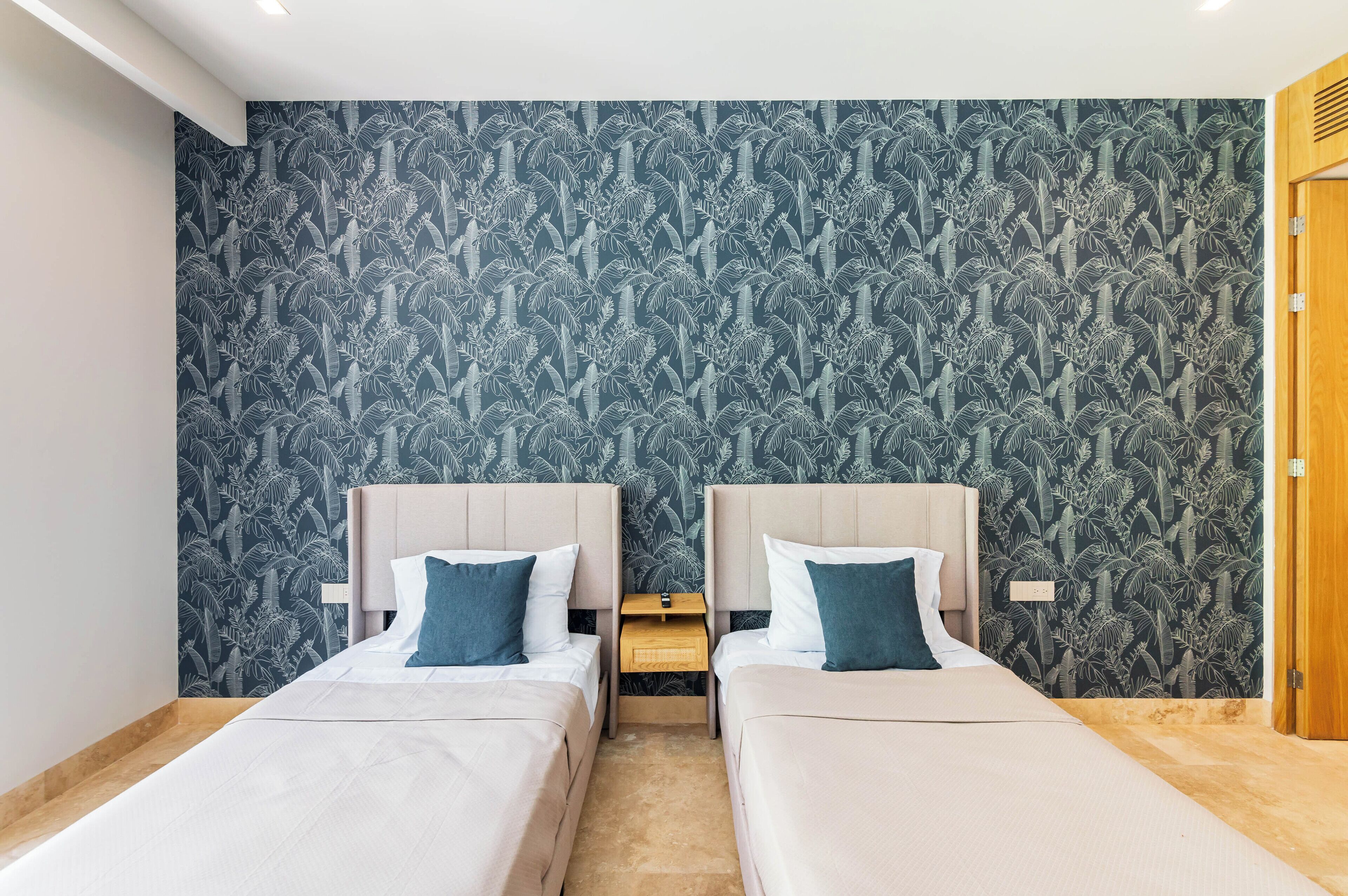 A twin room with two beds, a nightstand, and a wooden door.