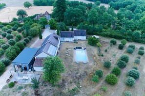 Una propiedad rural con una casa grande, piscina y follaje circundante.