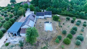 Une propriété située en zone rurale, comprenant une grande maison, une piscine et de nombreux espaces verts.