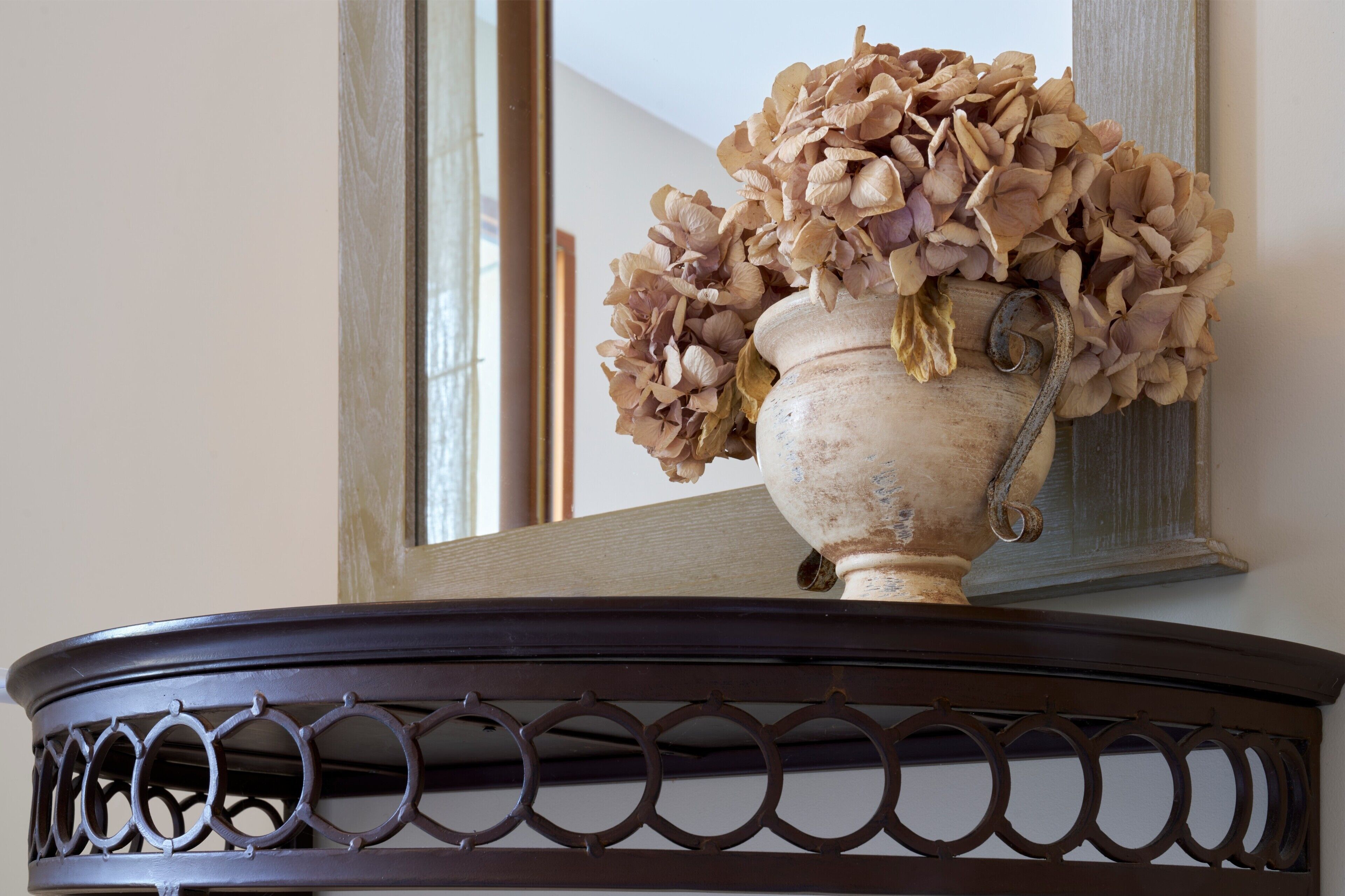 Un vase contenant des fleurs séchées, posé sur une table sombre et richement décorée.