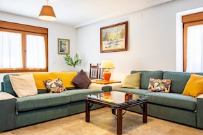 A living room with a green sofa, a glass coffee table, a painting on the wall, and a lamp. - Quercus Country House with Mountain Views, Wi-Fi, and Air Conditioning (Navaluenga)