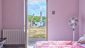 A bedroom with a bed, a fan, a radiator, and a view of an outdoor area with a pool and chairs. - Bed and Breakfast 'Safran' with Private Terrace, Shared Garden and Wi-Fi (Gabillou)