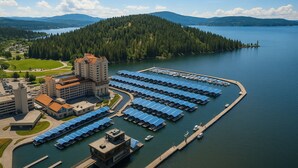 An aerial view of a lakeside hotel with a large building, a marina with numerous boats, and a forested island in the background. - Spacious 6-bedroom, Views, King Beds, Hot Tub, Game Room near downtown Spokane (Spokane)