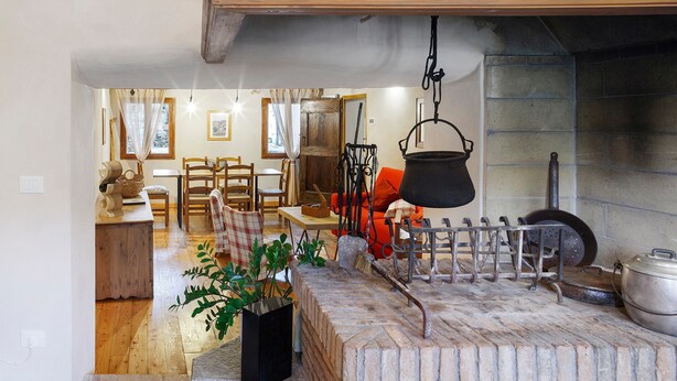 Un intérieur rustique avec une cheminée en briques, des meubles en bois et un pot suspendu.