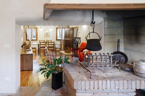 Un intérieur rustique avec une cheminée en briques, des meubles en bois et un pot suspendu.