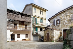 Un edificio de varios pisos con balcones, un muro de piedra y un patio de grava.